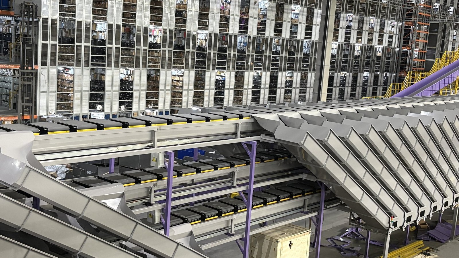 Automated warehouse sorting system with conveyors, vertical storage and cross-belt sorter
